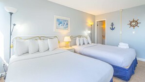 Camera matrimoniale con due letti, un comodino con lampada, una cornice, un anello a parete e una decorazione a forma di timone di nave.