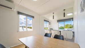 Ein Konferenzraum mit einem Holztisch, schwarzen und weißen Stühlen und großen Fenstern mit Blick auf Grünflächen.