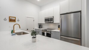 Een moderne keuken met witte kasten, roestvrijstalen apparatuur en een wit aanrecht.
