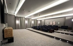 A modern cinema room with a carpeted floor, rows of seating, a large screen, and a wooden podium. - Vogue Downtown Forte Opera District near Burj Khalifa and Dubai Mall (Dubai)