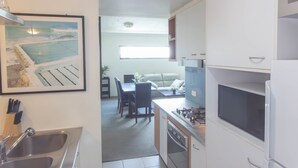 A compact kitchen with a sink, stove, microwave, and a dining area with a table and chairs. - Republic Apartment (Spring Hill)