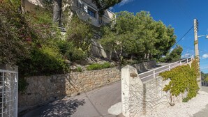 Une ruelle bordée d’un mur de pierre et d’un portail, qui mène à un bâtiment à la façade en pierre sur lequel on peut lire l’inscription « 301 ».
