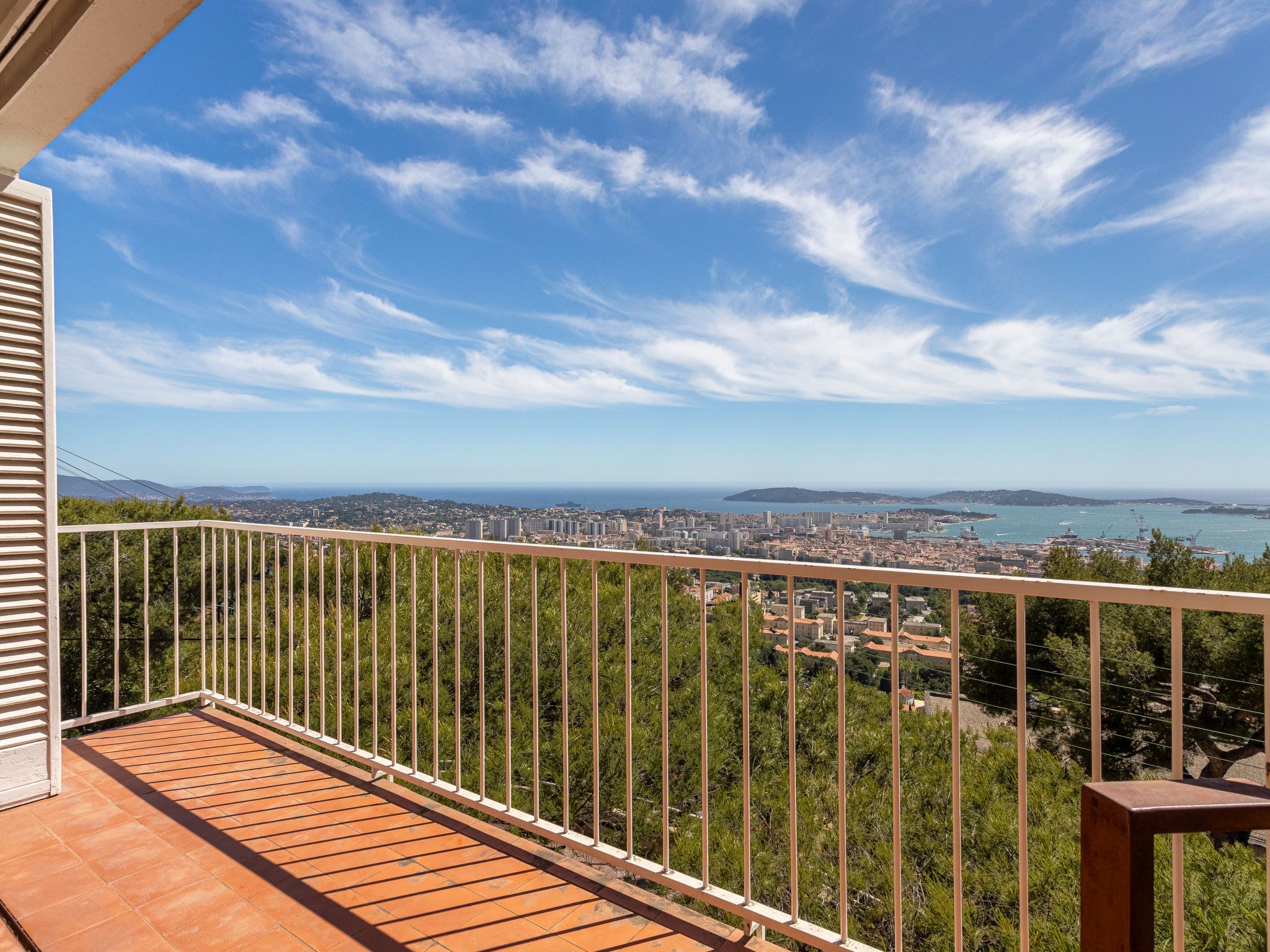 Ein Balkon mit Blick auf eine Küstenstadt, darunter Gebäude und das Meer.