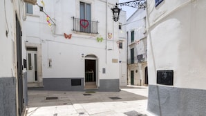 A narrow street with a building entrance, decorative butterflies, and a heart-shaped ornament.