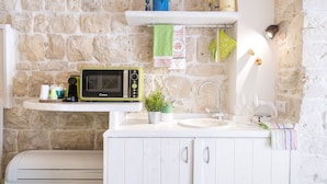 A kitchen with a stone wall, a microwave, a sink, and a printer.