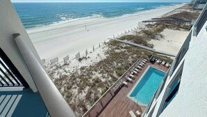 A beach view from a balcony with a pool and lounge chairs. - BROADMOOR 504 - BEACHFRONT RELAXATION! (Orange Beach)