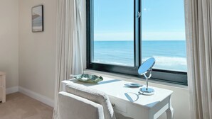 A room with a view of the ocean through a large window, a white desk with a mirror, and a beige chair. - BROADMOOR 504 - BEACHFRONT RELAXATION! (Orange Beach)