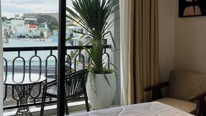 A hotel room with a balcony, a bed, a chair, a table, and a potted plant. - Dong Nhu 6 Hotel (Ho Chi Minh City)