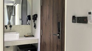 A modern bathroom with a large mirror, a wooden door, a sink, and a small black appliance. - Dong Nhu 6 Hotel (Ho Chi Minh City)