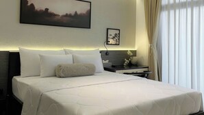 A modern hotel room with a large bed, a nightstand, a desk, and a window with curtains. - Dong Nhu 6 Hotel (Ho Chi Minh City)