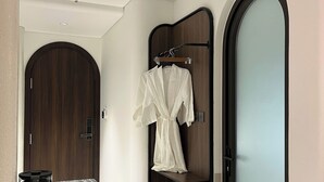 A hotel room with a marble countertop, a robe hanging on a wooden rack, and a large mirror. - Dong Nhu 6 Hotel (Ho Chi Minh City)