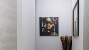 A narrow hallway with a painting on the wall, a vase with dried plants, and a framed picture. - Hope residence Bassam (Modest grand bassam)