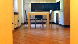 A kitchen with a dining table and chairs, a tiled floor, and cabinets.