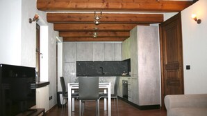 A compact living space with a dining area, kitchenette, and a television.