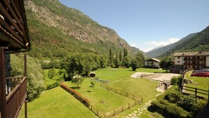 A mountainous landscape with a well-maintained garden, a wooden fence, and a building with a sloped roof.