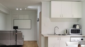 Een knus woongedeelte met een kitchenette, een bank en een projectorinstallatie.