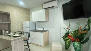 Una cocina compacta con refrigerador integrado, un lavamanos y una zona de comedor con sillas.