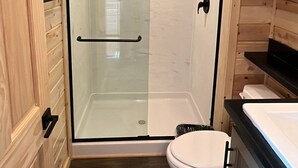 A compact bathroom with a glass-enclosed shower, a toilet, and a sink. - 061B Grand Canyon Chalet near South Rim King Bed (Williams)