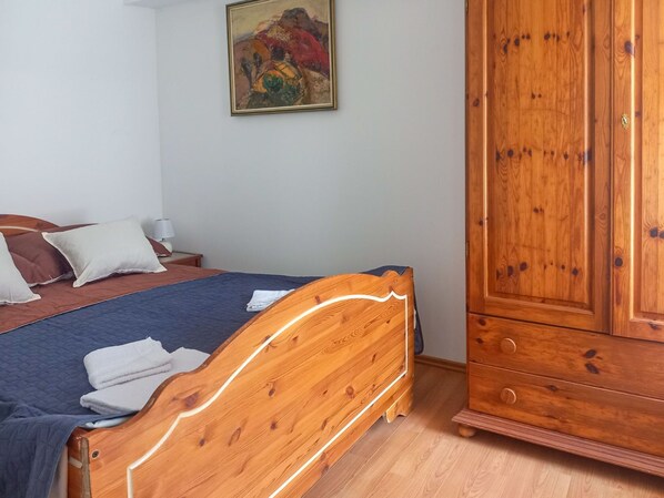 A bedroom with a wooden bed, a wardrobe, and a painting on the wall.