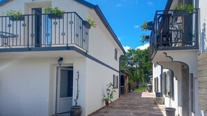 Una calle estrecha flanqueada por edificios de dos pisos, cada uno con balcones y macetas.