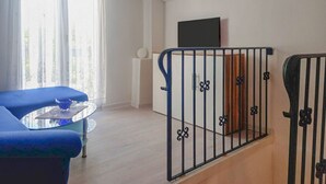 Una sala de estar moderna con un sofá azul, una mesa de centro de vidrio y una escalera con barandilla de metal.