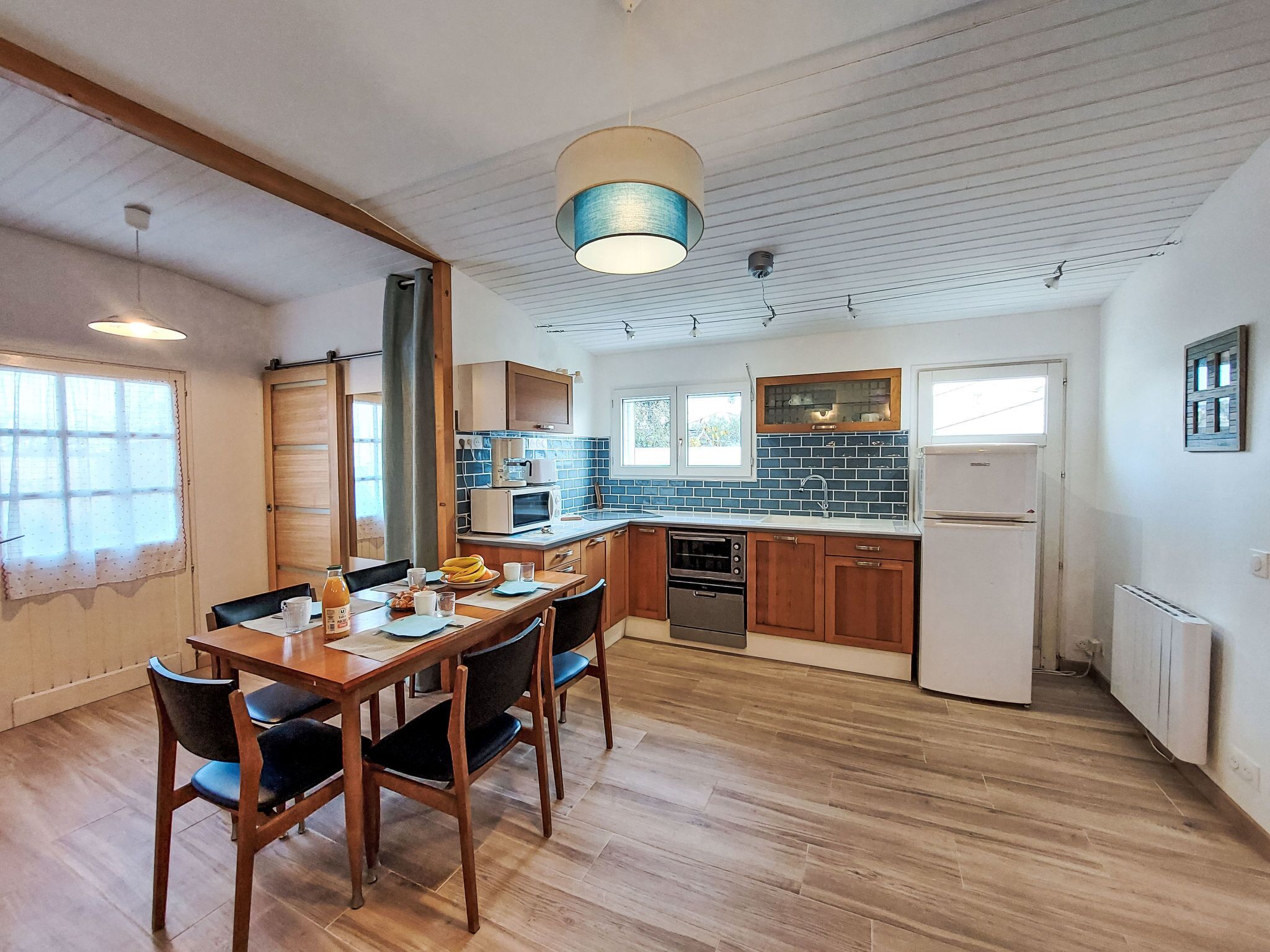 Kompakti keittiö, jossa on ruokailutila, puulattia ja kattotuuletin.