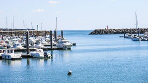 A marina with numerous boats docked, a rocky breakwater, and a lighthouse in the distance. - Charme de la Petite Bosse by Interhome (Ile de Noirmoutier)