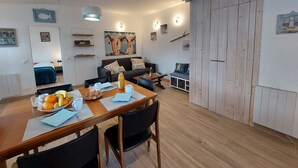 A cozy living room with a wooden dining table, a sofa, and a painting on the wall. - Charme de la Petite Bosse by Interhome (Ile de Noirmoutier)