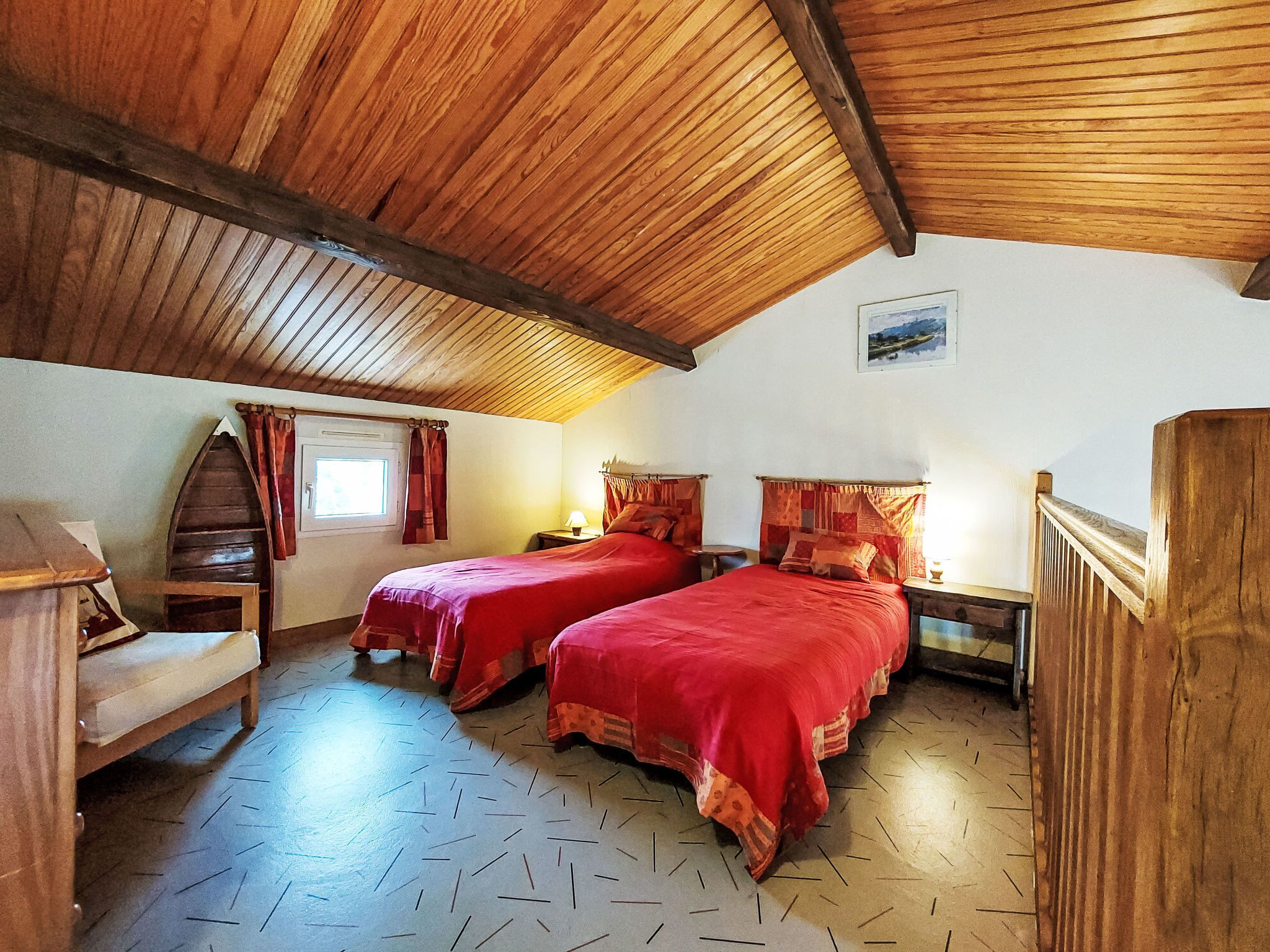 Une pièce confortable avec deux lits, des poutres en bois au plafond, une petite fenêtre et une chaise en bois.