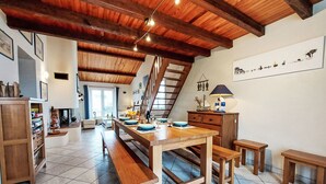 A spacious dining area with a wooden table set for four, benches, and a staircase leading to an upper level.