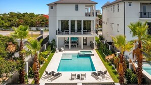 A two-story residential building with a swimming pool, outdoor seating, and palm trees. - Scarlett's Beach Heaven - Luxury Beach House with Rooftop Views and Pool (Miramar Beach)