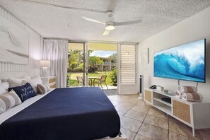 Quarto com cama, ventilador de teto, televisão e vista para o exterior.
