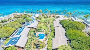 Luchtbeeld van een resort met zonnepanelen, een zwembad en een strand.