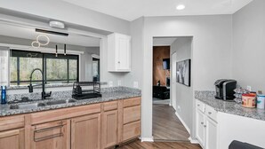 Una cocina moderna con encimeras de granito, armarios de madera y vistas al exterior a través de amplios ventanales.