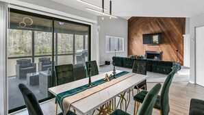 Un comedor moderno con una mesa larga, sillas tapizadas en verde y vista a un lago a través de amplios ventanales.