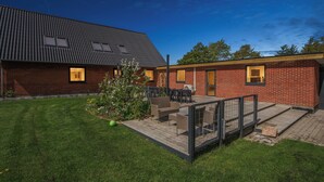 Ein Gebäude mit Ziegelaußenwand, einer Holzdielen-Terrasse und klarem Himmel.