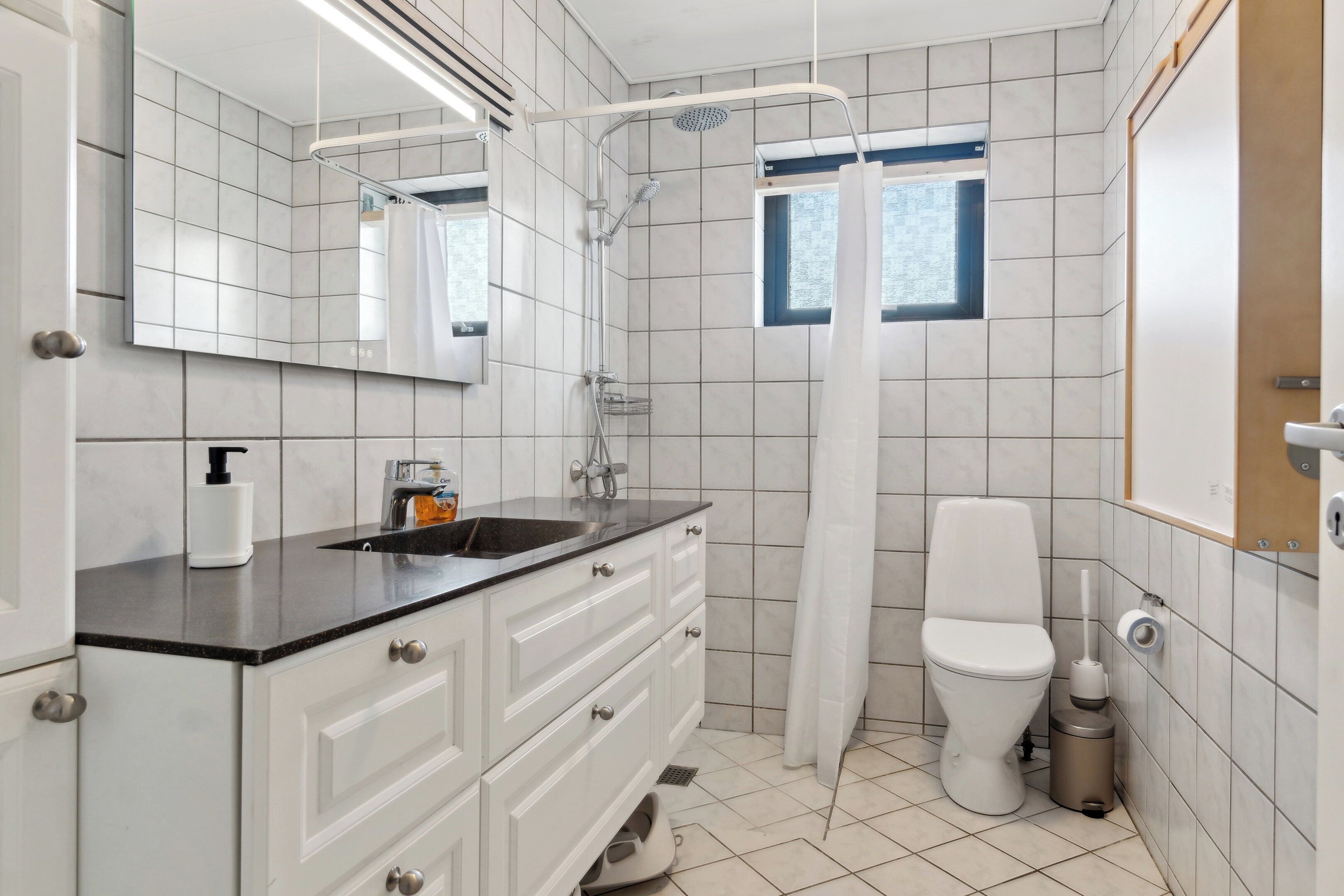 Een moderne badkamer met douche, toilet en wastafel.