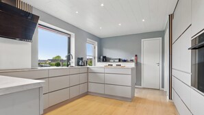 Eine moderne Küche mit einer großen Kochinsel, eingebauten Geräten und Blick ins Freie.