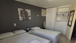 A hotel room with two beds, a desk, a chair, a wardrobe, and a painting on the wall. - ACOMODAÇÕES RG APARTAMENTOS SÃO PAULO SP (São Paulo)