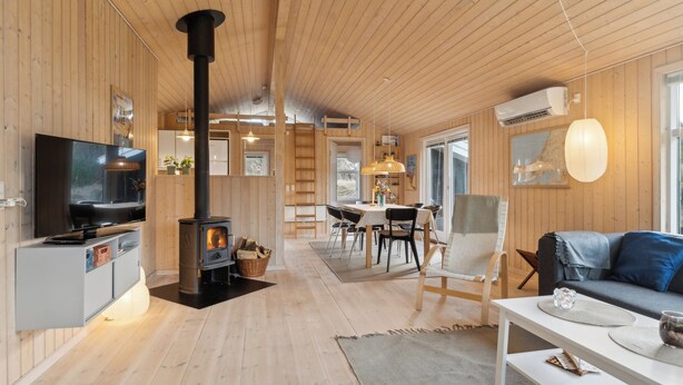Ein Holzinnenraum mit Fernseher, Kamin, Essbereich und einer Couch.
