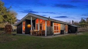 Ein modernes Haus mit einer großen Veranda, einem Essbereich und einer Garage.