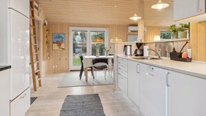Eine moderne Küche mit weißen Schränken, einem eingebauten Geschirrspüler und einem Fenster mit Blick auf einen Garten.