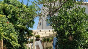 A pathway leading to a building with a staircase, surrounded by greenery and plants. - Beachfront apartment with pool & ocean views, 4 mins walk to Beach. Sleeps 7 (Quinns Rocks)