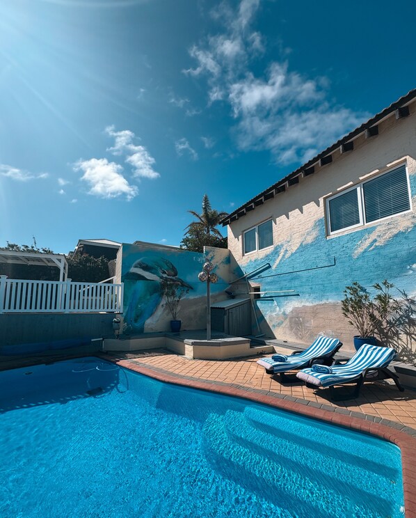 A swimming pool with lounge chairs and a mural wall. - Beachfront apartment with pool & ocean views, 4 mins walk to Beach. Sleeps 7 (Quinns Rocks)