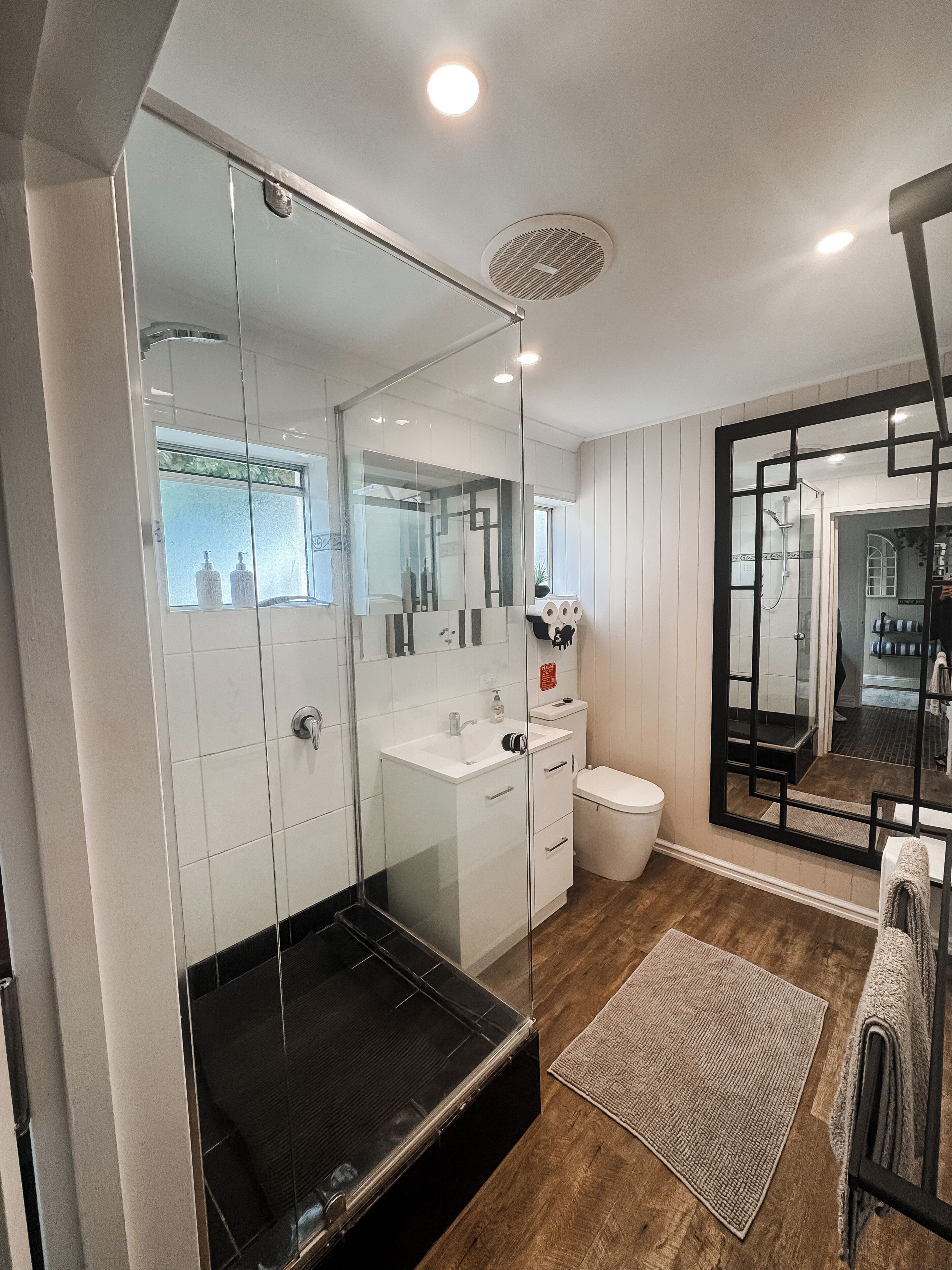 Un baño moderno con cabina de ducha de vidrio, un lavabo blanco y un inodoro.