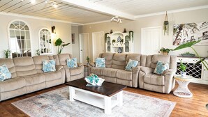 A spacious living room with two beige sofas, a wooden coffee table, and a patterned rug. - Beachfront apartment with pool & ocean views, 4 mins walk to Beach. Sleeps 7 (Quinns Rocks)