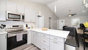 A modern kitchen with white cabinetry, stainless steel appliances, and a large island. - Charming Cary Home~Centrally Located~Comfortable beds (Cary)