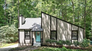 A single-story house with a front porch, a small garden, and a pathway leading to the entrance. - Charming Cary Home~Centrally Located~Comfortable beds (Cary)