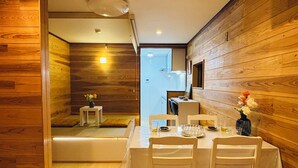A dining area with a wooden interior, a table set for four, and a view into the kitchen.