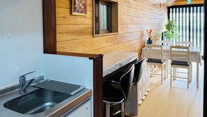 A modern kitchen with a wooden accent wall, a built-in sink, and bar stools.
